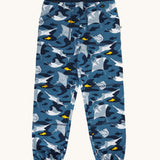 Frugi organic cotton joggers laid flat . In dark blue and navy trim with a repeating grey manta ray and shark print. 