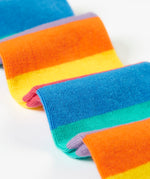 A close up of the bottom half of the light purple Frugi organic cotton tights laid flat showing the striped rainbow design.