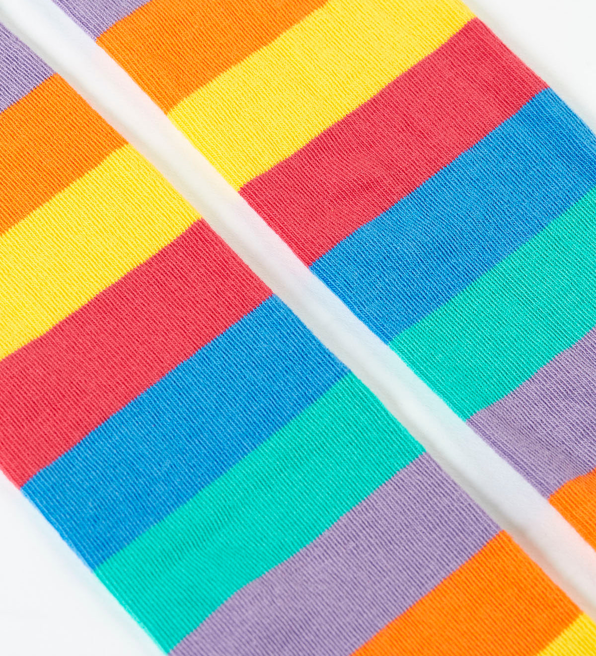A close up of the rainbow stripe design on the bottom half of the light purple Frugi leggings.