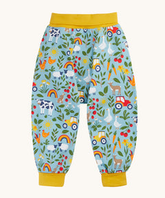 Frugi organic cotton parsnip pants laid flat in light blue and yellow trim with a repeating farm inspired print.
