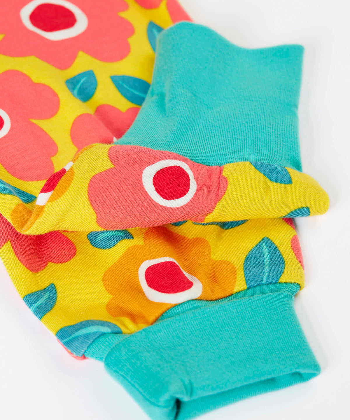 A close up of the repeating floral print and turquoise leg cuffs on the bright yellow pants