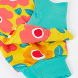 A close up of the repeating floral print and turquoise leg cuffs on the bright yellow pants