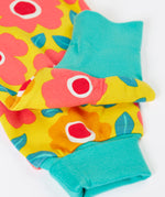 A close up of the repeating floral print and turquoise leg cuffs on the bright yellow pants