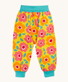 Frugi organic cotton parsnip pants laid flat. In bright yellow with a turquoise waist band and leg cuffs. Has a repeating floral print. 