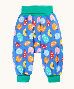Frugi organic cotton parsnip pants laid flat in light blue and turquoise trim with a repeated ladybird print