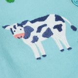 A close up of a black and white cow design on the light blue Frugi dungaree 