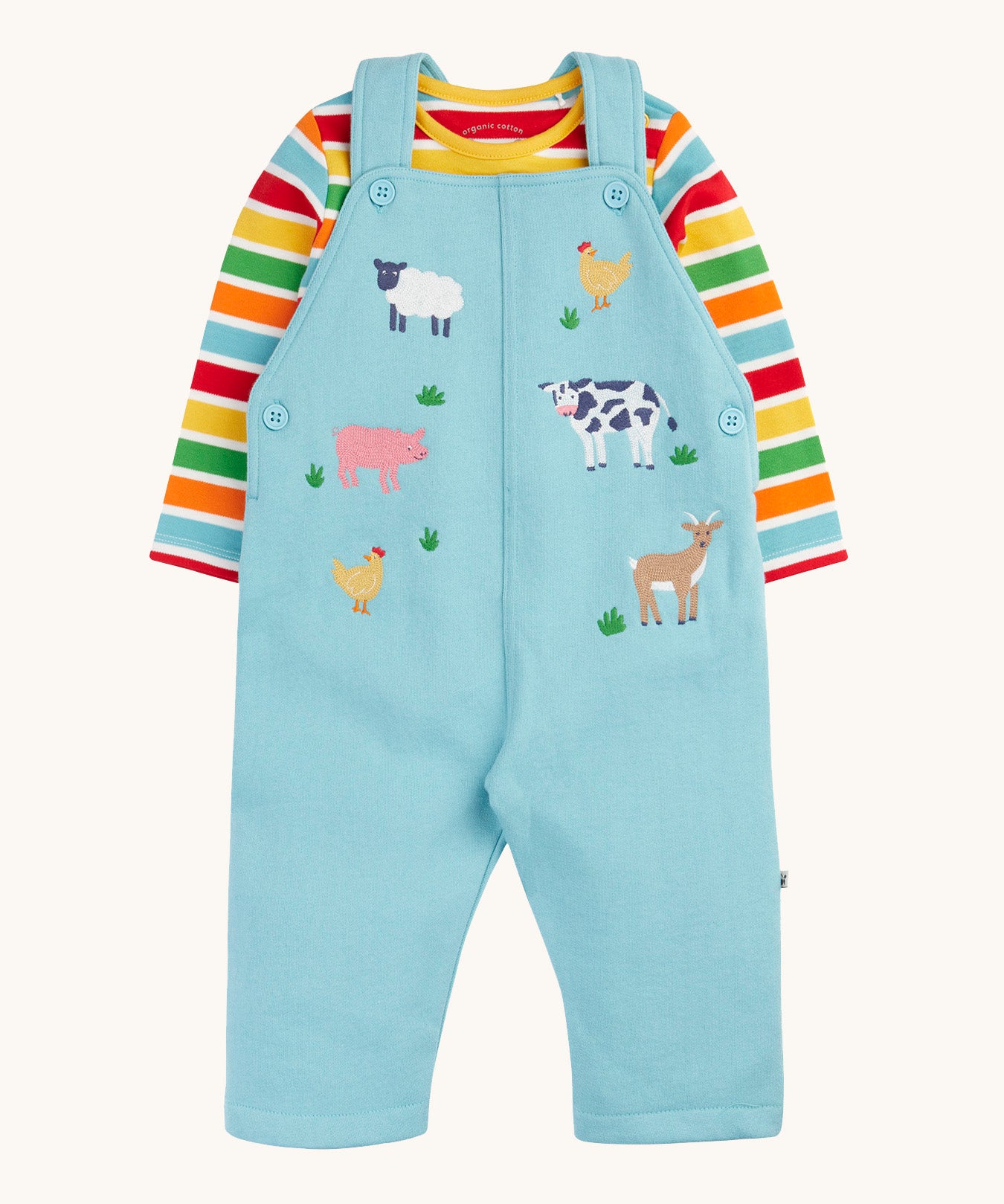 Frugi light blue organic cotton dungaree with farm animals on the front with a rainbow striped long sleeve top underneath as an outfit