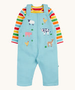 Frugi light blue organic cotton dungaree with farm animals on the front with a rainbow striped long sleeve top underneath as an outfit
