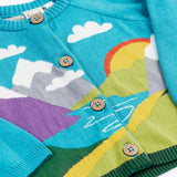 A close up of the Frugi kid reva knitted cardigan in blue/mountain scene showing the mountain scene detail and button  fasteners. 