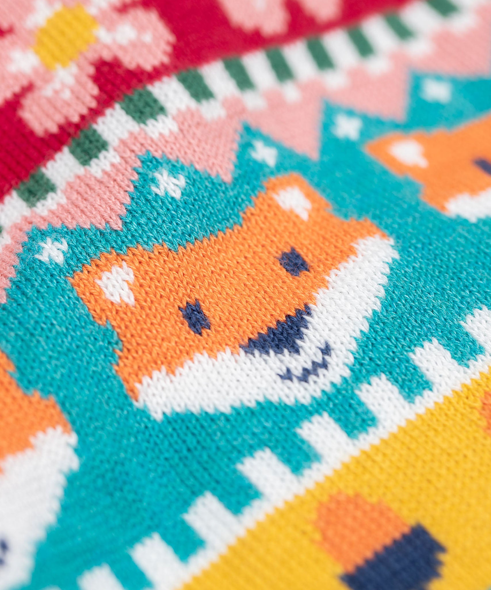 A close up of the Frugi kids robyn fairisle cardigan in fox showing the woodland inspired fairisle design detail on organic cotton fabric.
