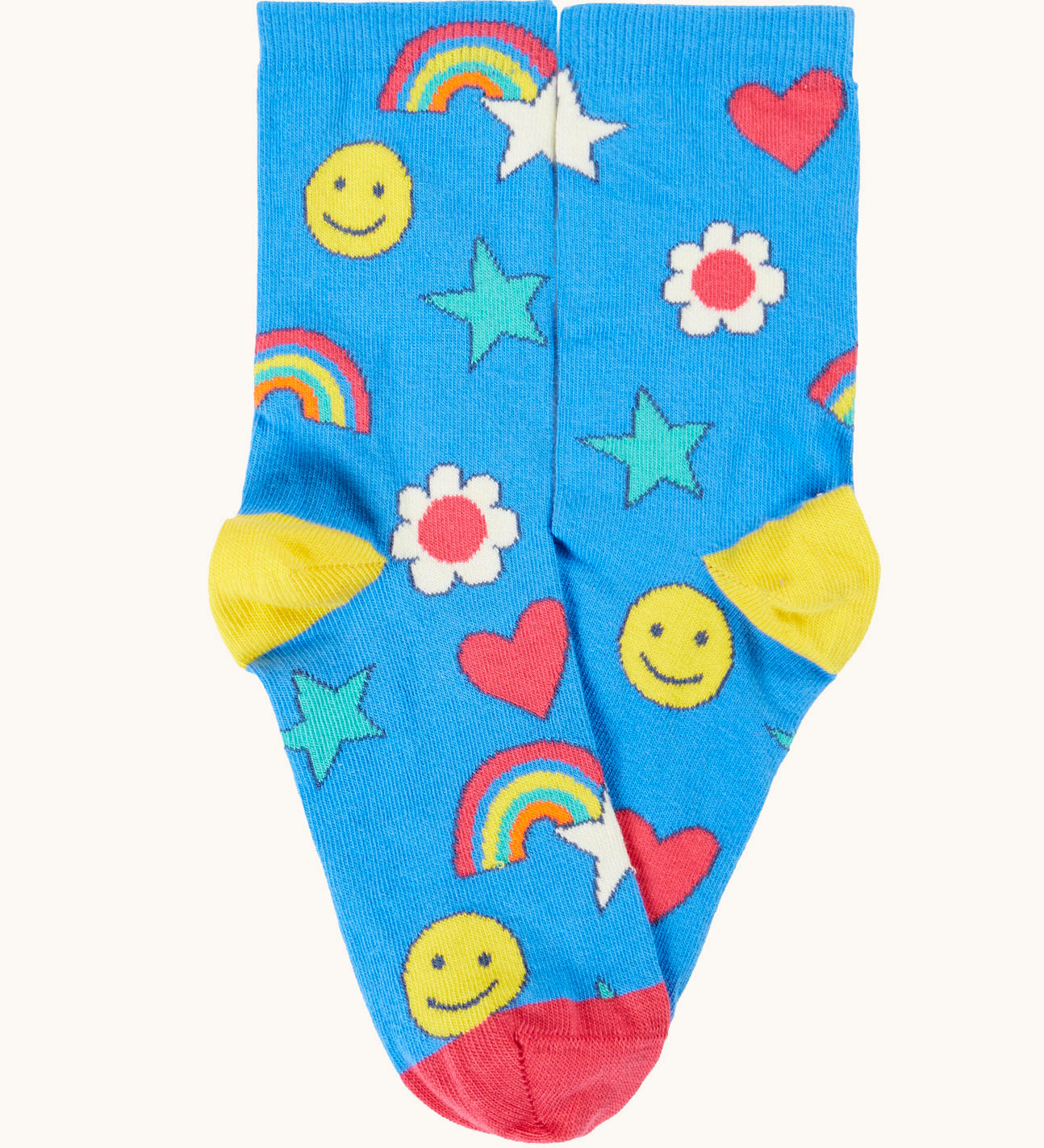 A blue playful happy themed Frugi organic cotton sock laid flat with a repeating star, rainbow and smiling face print.