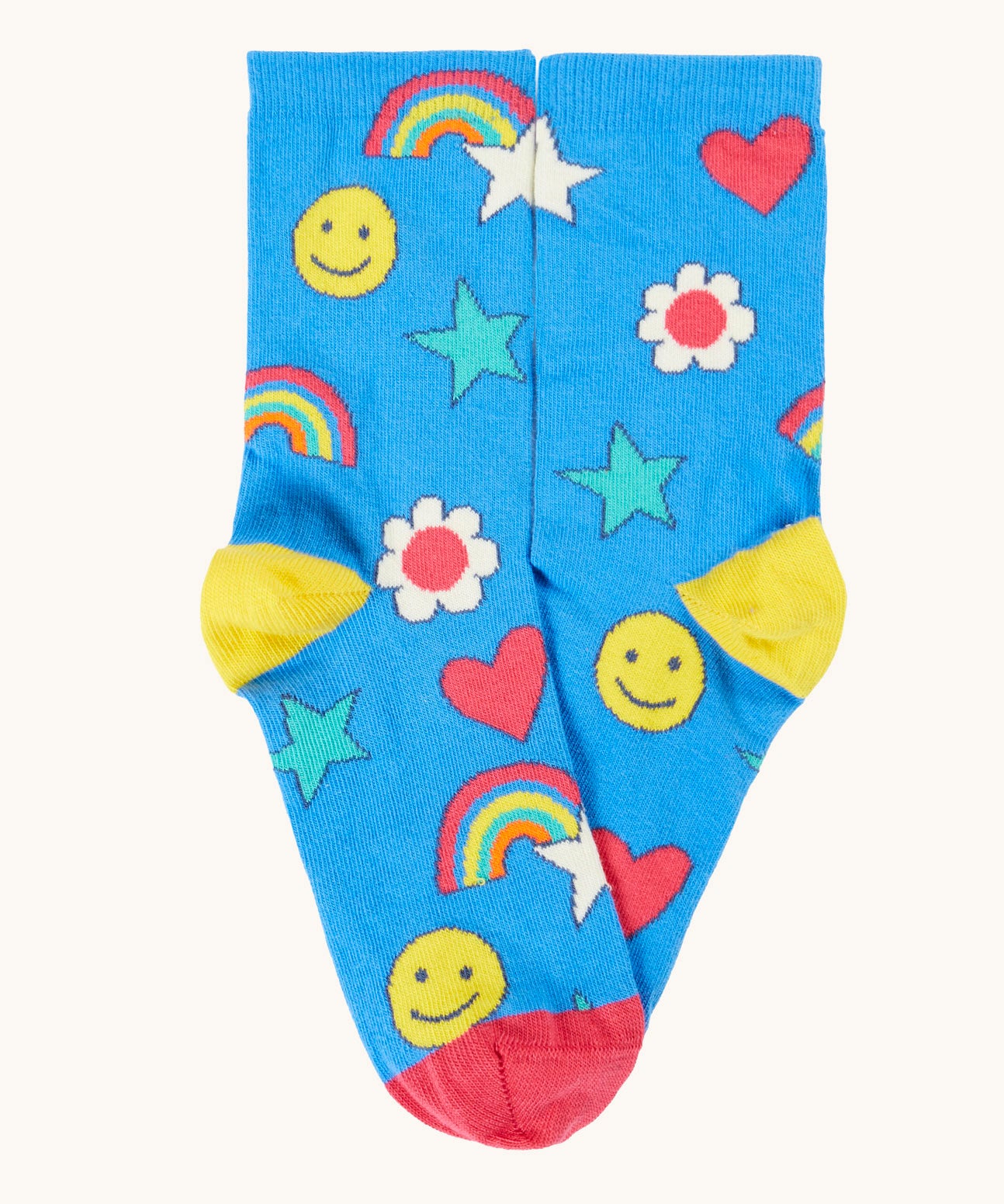 A blue playful happy themed Frugi organic cotton sock laid flat with a repeating star, rainbow and smiling face print.