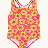 Frugi recycled plastic swimsuit laid flat. In pink with a repeating yellow sunflower and bee design.