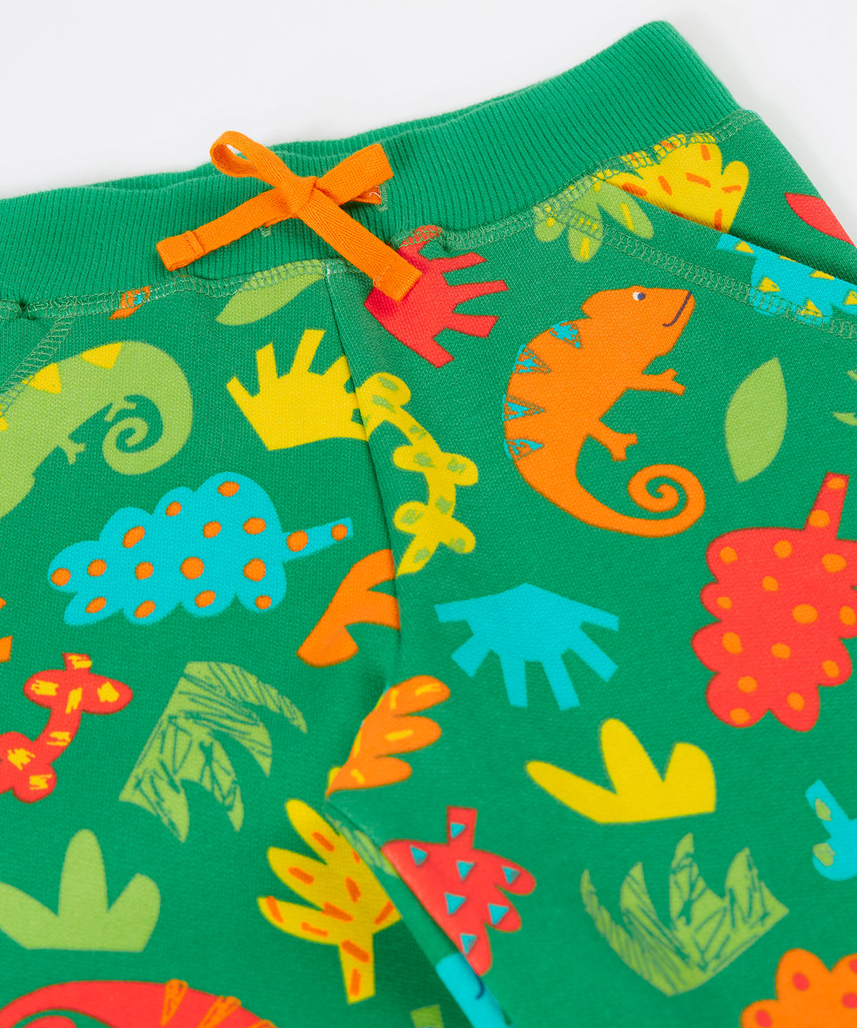 A close up of the orange waist tie and the repeated chameleon and leaves design on the Frugi green samson shorts