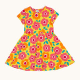 Frugi skater dress laid flat. In bright yellow with a repeating pink and orange floral print