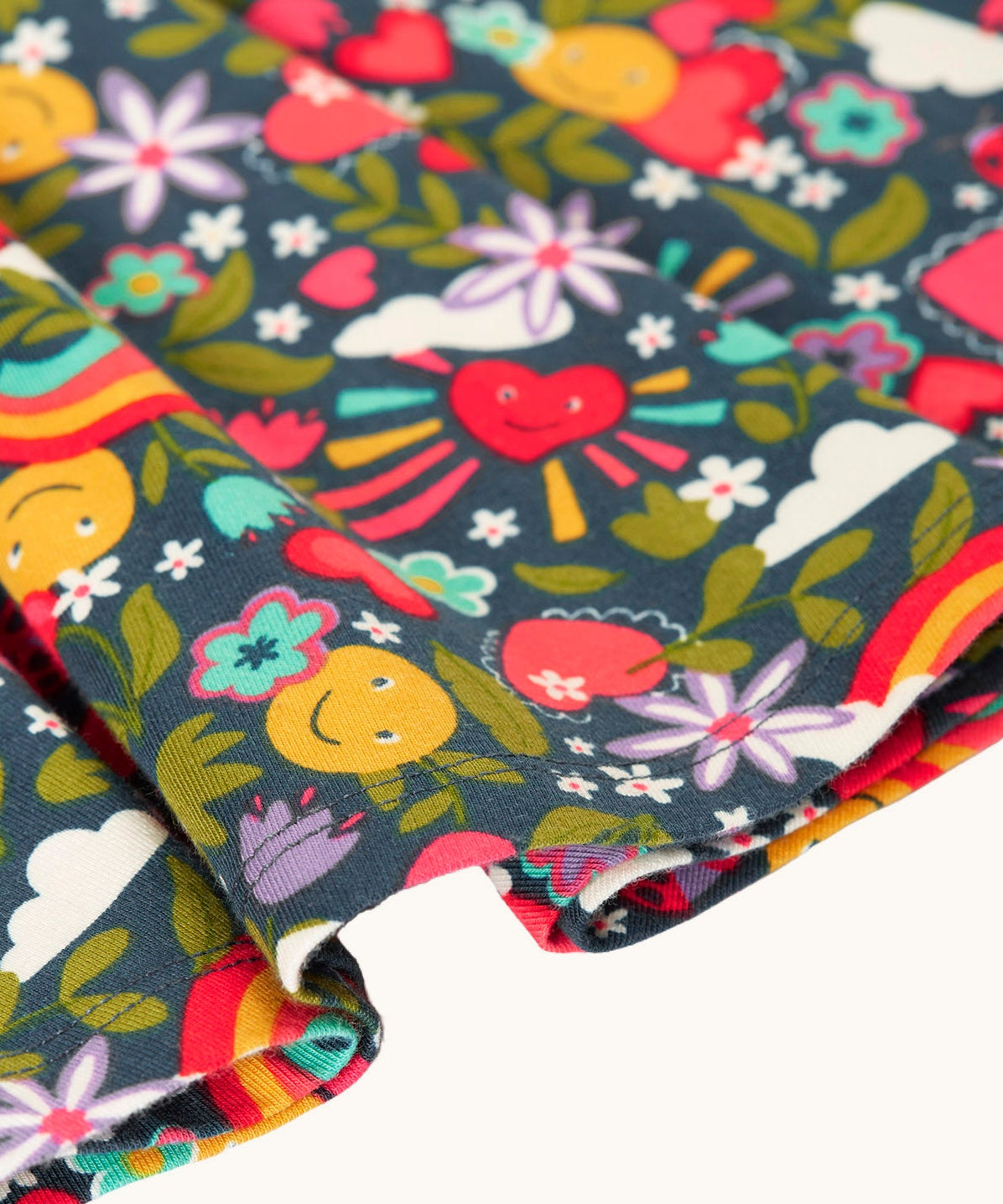 A close up of the navy Frugi organic cotton skater dress laid flat showing the frill detail and happy themed repeating print