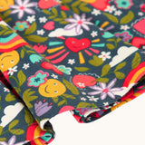 A close up of the navy Frugi organic cotton skater dress laid flat showing the frill detail and happy themed repeating print