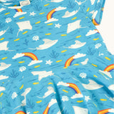 A close up of the light blue Frugi skater dress laid flat showing the repeating grey manta ray and rainbow print