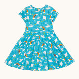 Frugi organic cotton skater dress laid flat. In light blue with a repeating grey manta ray and rainbow print