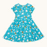 Frugi organic cotton skater dress laid flat. In light blue with a repeating grey manta ray and rainbow print