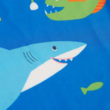 A close up of the shark and angler fish design on the blue Frugi rash vest laid flat.