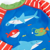 A close up of blue with red and white stripes frugi rash vest showing the different sea creatures and green collar trim.