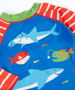 A close up of blue with red and white stripes frugi rash vest showing the different sea creatures and green collar trim.