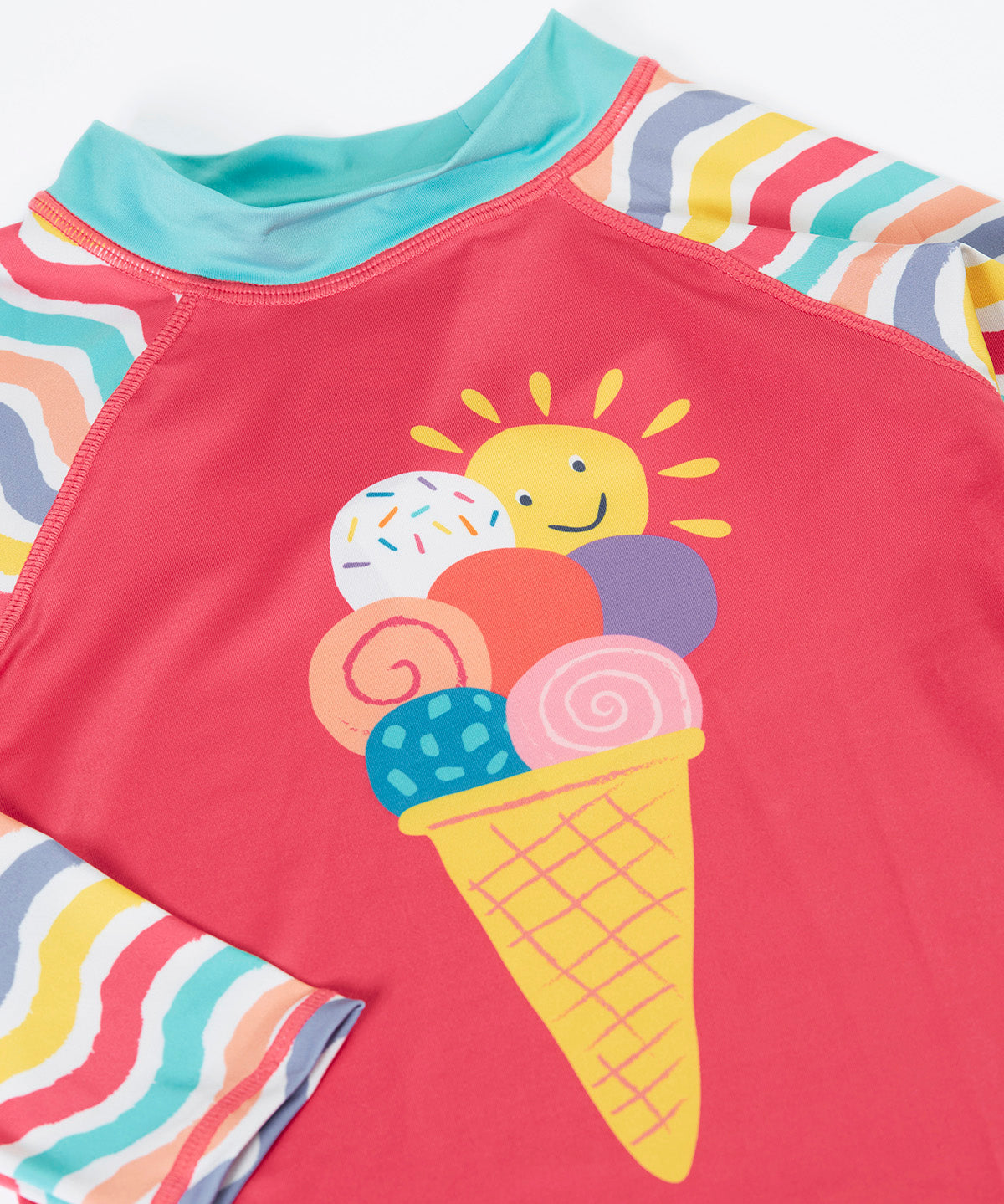 A close up of the light pink recycled plastic rash vest laid flat showing the detailing on the playful ice cream design on the front and pastel wavy striped design on the sleeves