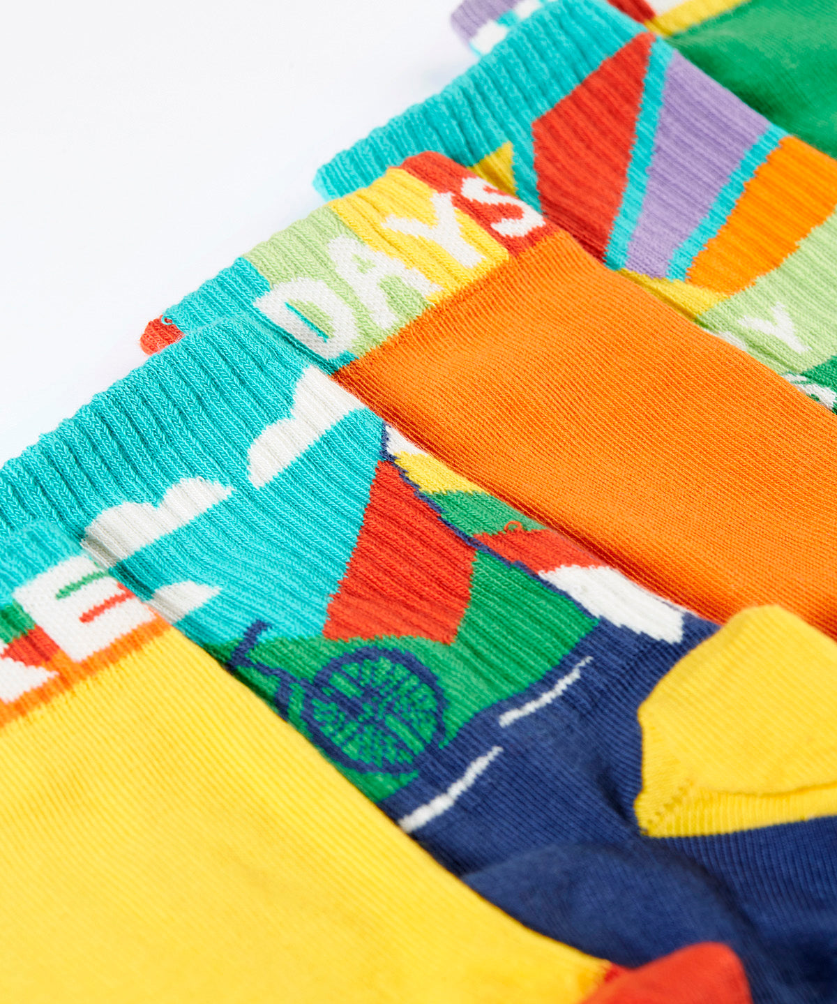 A close up of the Frugi adventure themed multipack socks laid flat. In different colours and designs with a elasticated cuff
