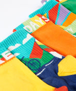 A close up of the Frugi adventure themed multipack socks laid flat. In different colours and designs with a elasticated cuff