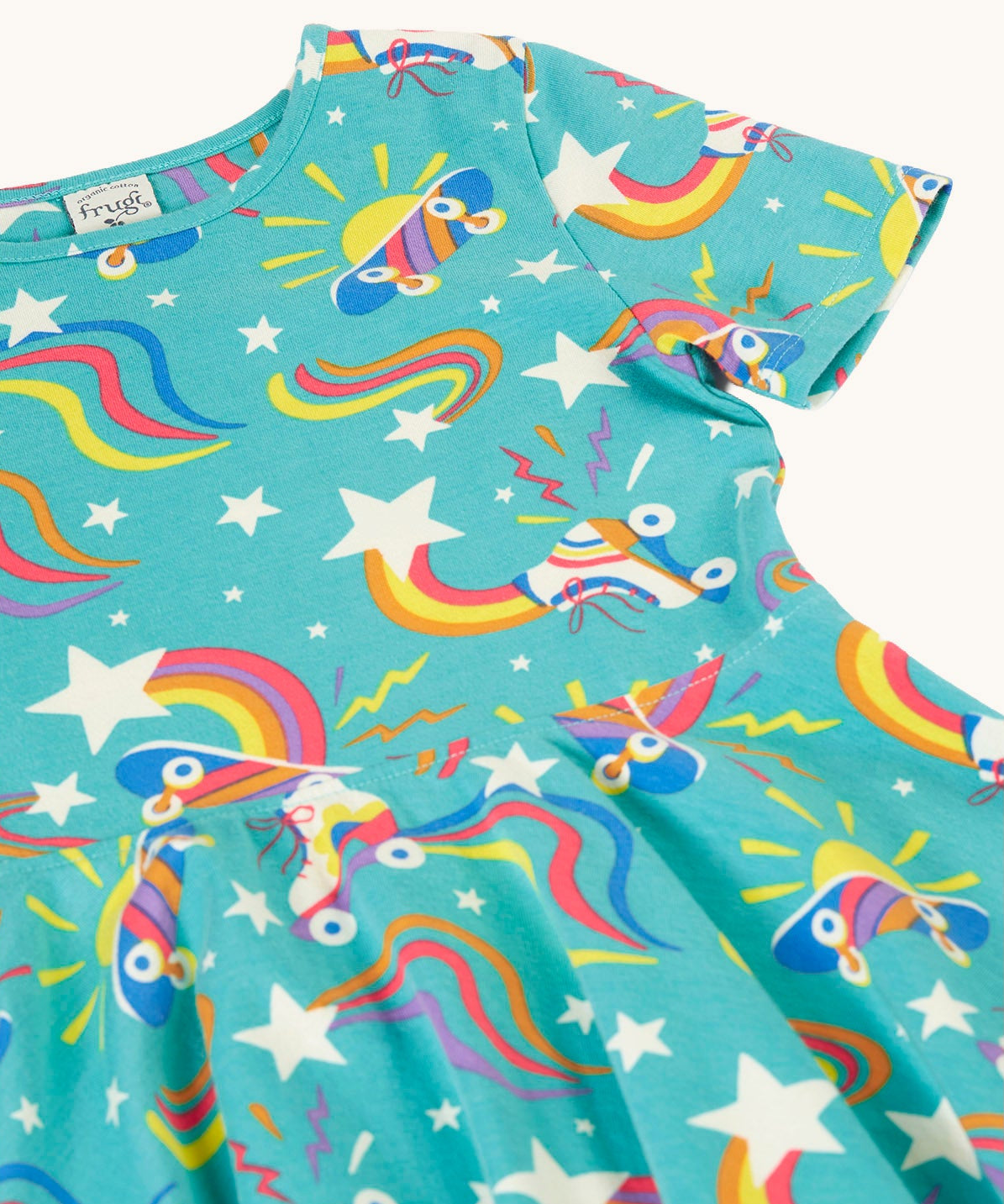 A close up of the turquoise skater dress laid flat showing the repeating roller blades and skateboard prints with colourful shapes.