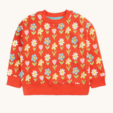Frugi organic cotton sweatshirt laid flat. In red with a repeating pastel coloured flower print.