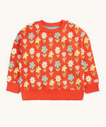 Frugi organic cotton sweatshirt laid flat. In red with a repeating pastel coloured flower print.
