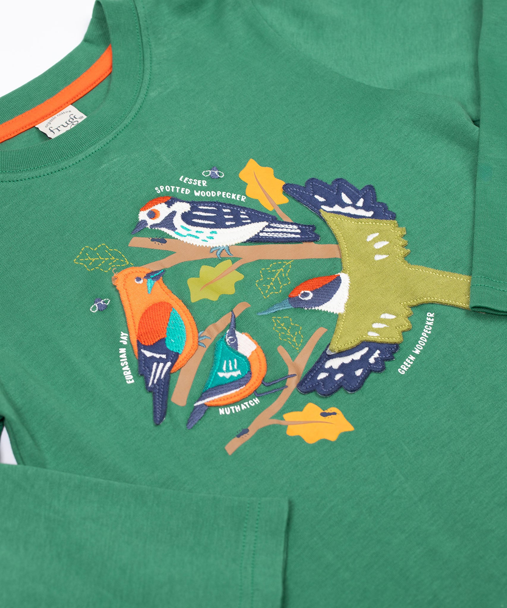 A close up of the Frugi kids terrific applique top in holly green/birds showing the neck and applique detail on dark green organic cotton fabric.