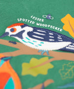A close up of the Frugi kids terrific applique top in holly green/birds showing the woodpecker applique detail on dark green organic cotton fabric.