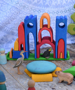 Gluckskafer blue castle in a play setup on a wooden surface. Features wooden animal figures