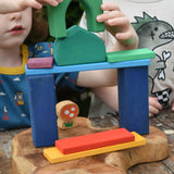 Children playing with the Glückskäfer building block set stacking pieces with Grimm's 1001 nights blocks with a Lanka Kade Babipur mushroom in the background.