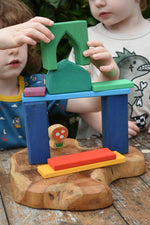 Children playing with the Glückskäfer building block set stacking pieces with Grimm's 1001 nights blocks with a Lanka Kade Babipur mushroom in the background.
