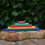 Glückskäfer colorful wooden rectangular blocks stacked in size order on a carved wooden board outdoors.