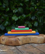 Glückskäfer colorful wooden rectangular blocks stacked in size order on a carved wooden board outdoors.