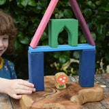 Child playing with the Glückskäfer building block set stacking pieces with Grimm's 1001 nights blocks with a Lanka Kade Babipur mushroom placed underneath.