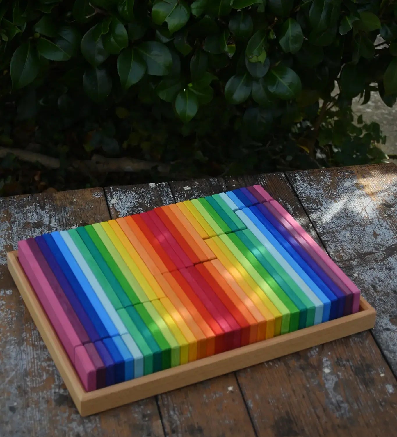 Glückskäfer 64 building slats in flat storage box tray placed on a wooden surface.