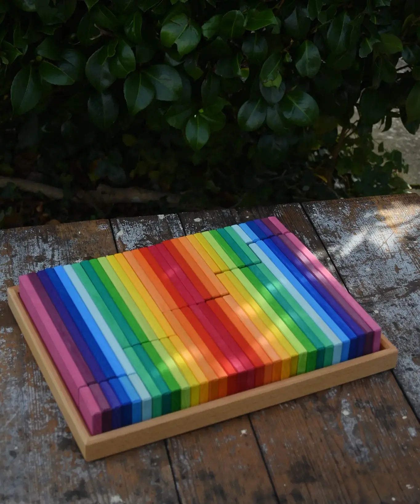 Glückskäfer 64 building slats in flat storage box tray placed on a wooden surface.