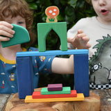 Children playing with the Glückskäfer building block set stacking pieces with Grimm's 1001 nights blocks with a Lanka Kade Babipur mushroom in the background.