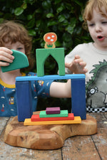 Children playing with the Glückskäfer building block set stacking pieces with Grimm's 1001 nights blocks with a Lanka Kade Babipur mushroom in the background.