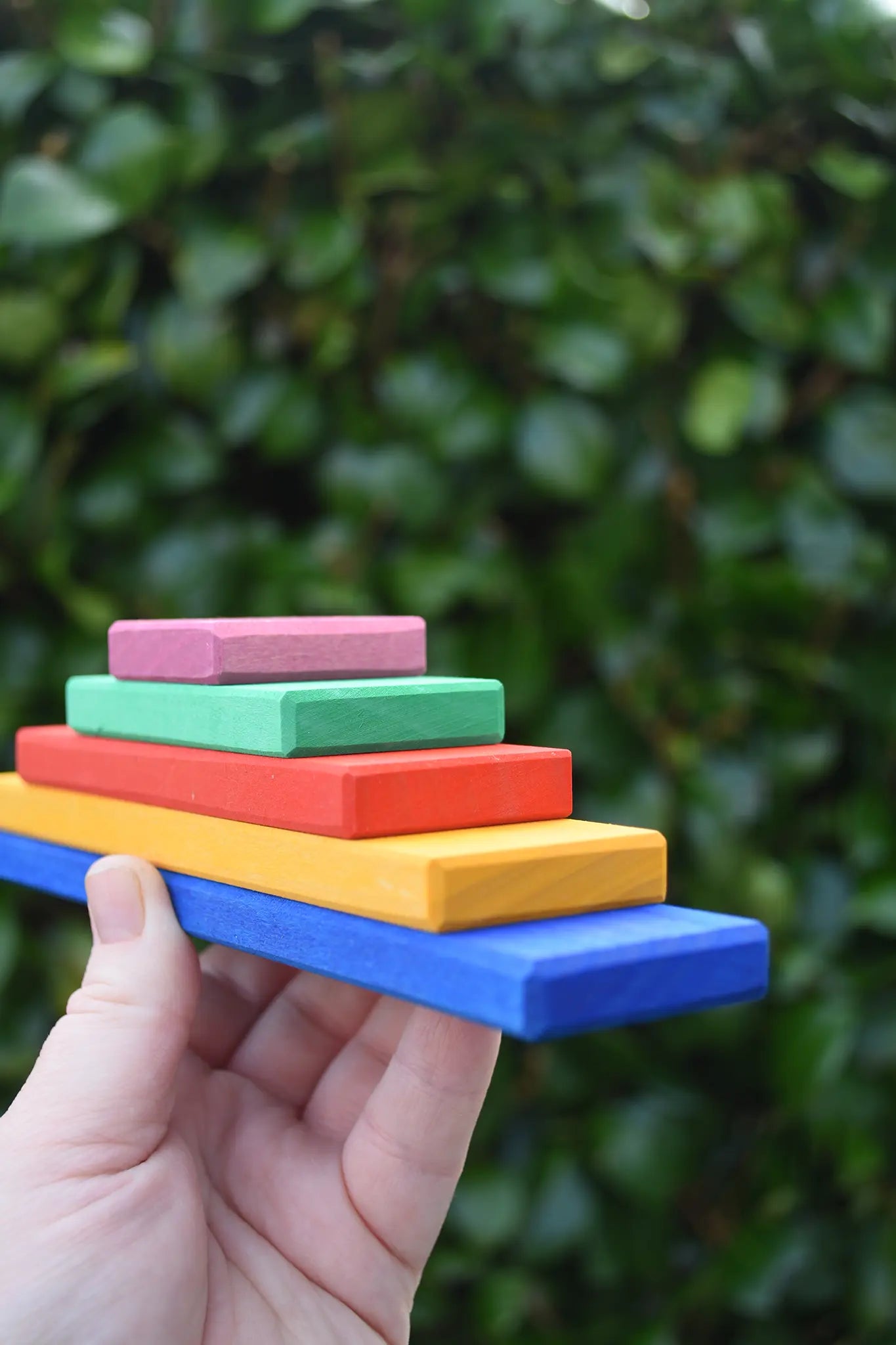 Stack of Glückskäfer building slats arranged in size order in an adult's hand.