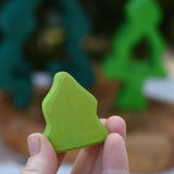 Smallest piece from the Glückskäfer 6-Piece Fir Tree wooden tree stacking toy in an adult's hand.