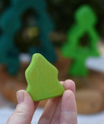 Smallest piece from the Glückskäfer 6-Piece Fir Tree wooden tree stacking toy in an adult's hand.