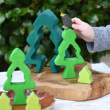 Child playing with the Glückskäfer 6-Piece Fir Tree wooden tree with the pieces placed on a wooden surface The child has an Ostheimer black bird in his hand. 