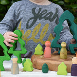 Child playing with the Glückskäfer 6-Piece Fir Tree wooden tree stacking toy in a small world play scene with Grapat wild crew animal nins. 